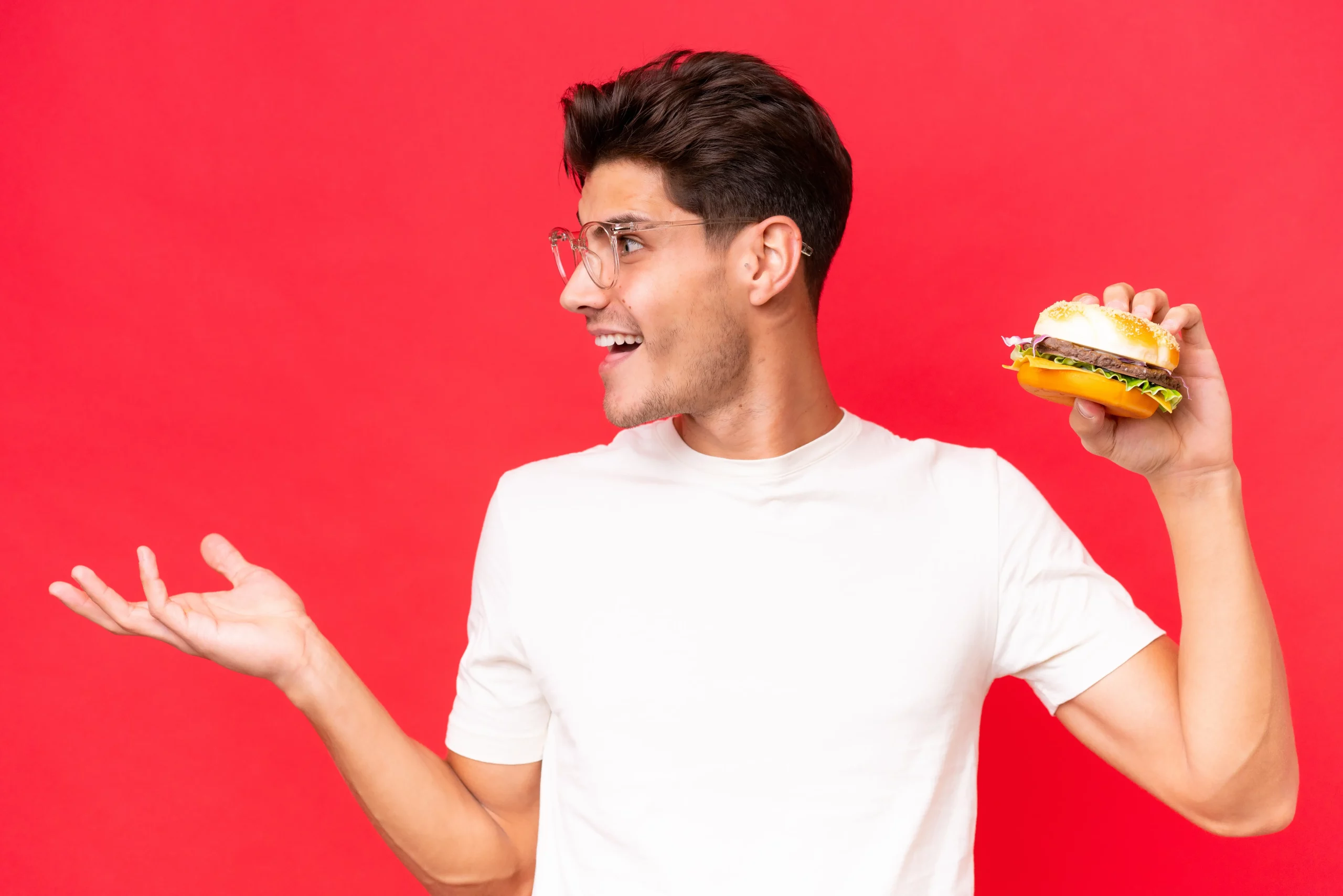 Young guy holding a burger in one hand in Salt Lake City, UT | Santosh Yoga Institute