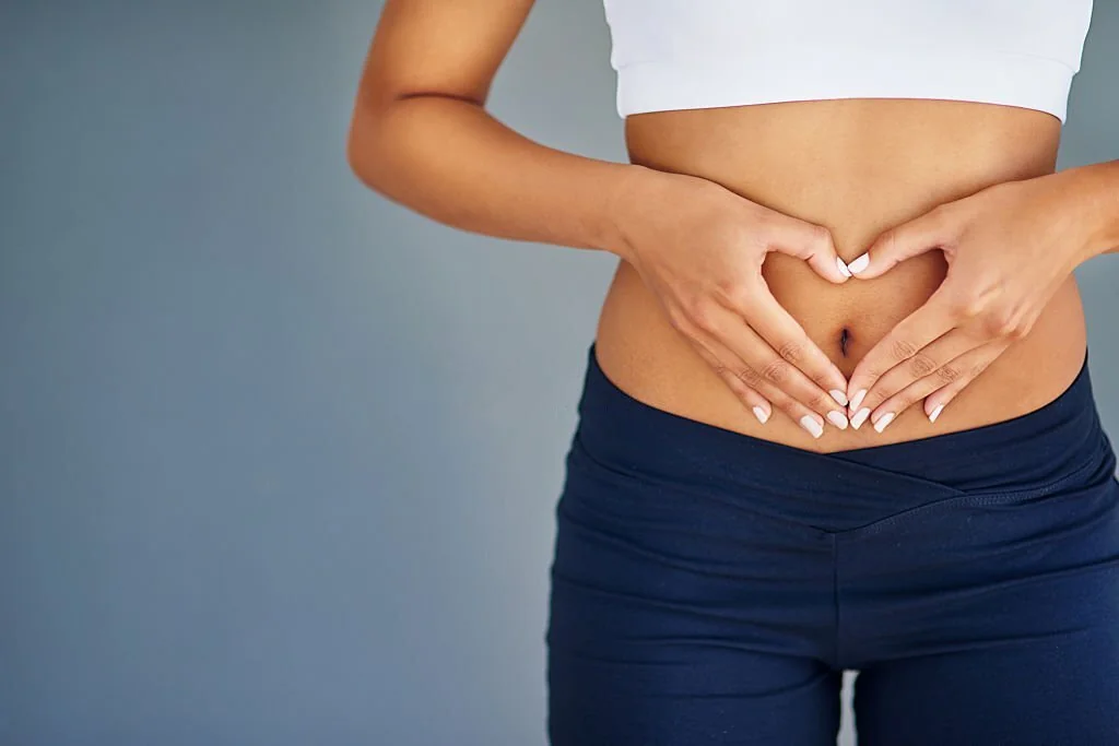 Fit young woman making a heart-shaped gesture over her stomach in Salt Lake City, UT | Santosh Yoga Institute