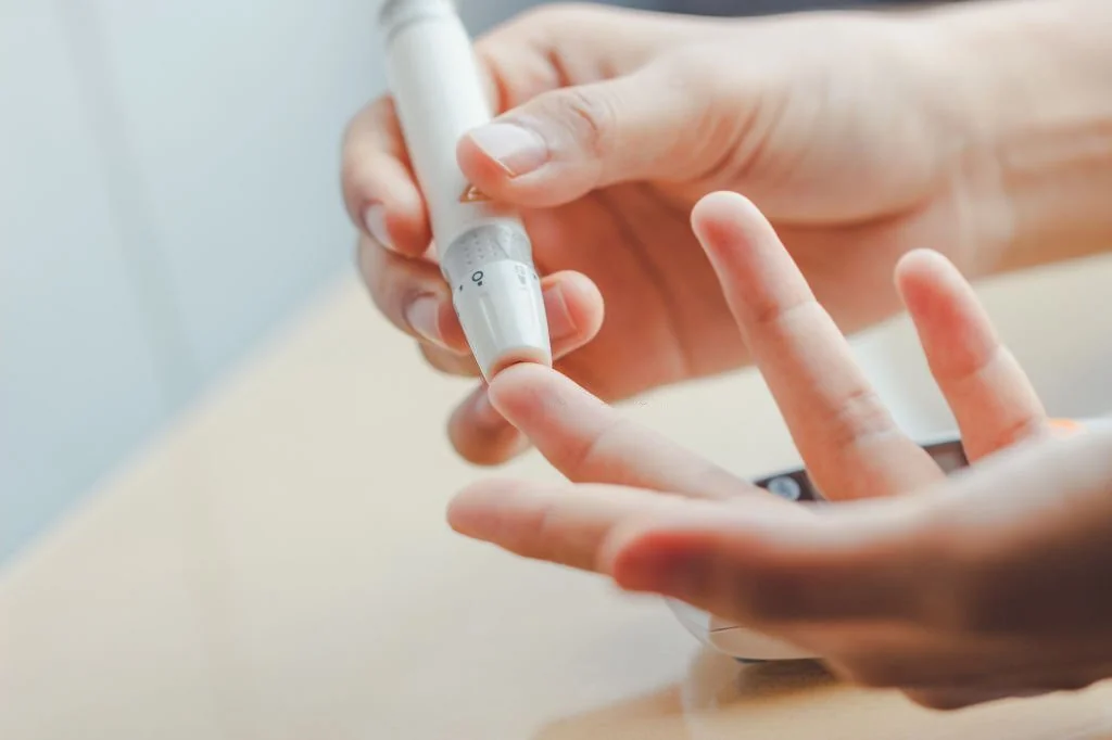 Woman hands using lancet on finger to check blood sugar level by Glucose meter in Salt Lake City, UT | Santosh Yoga Institute
