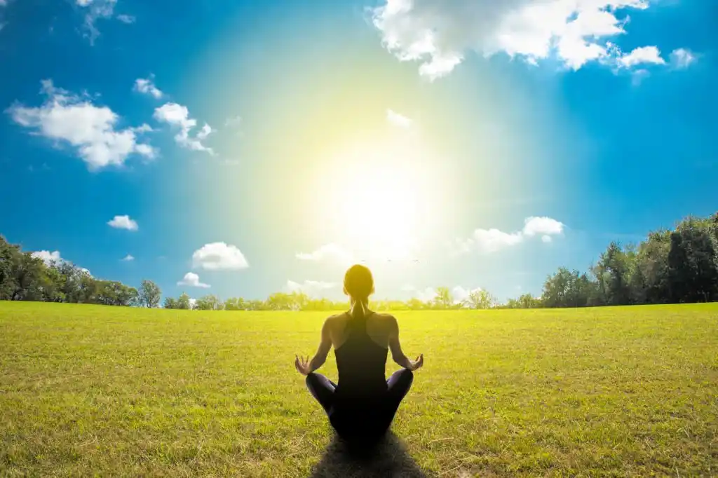 Young female sitting in beautiful garden doing meditation yoga in Salt Lake City, UT | Santosh Yoga Institute